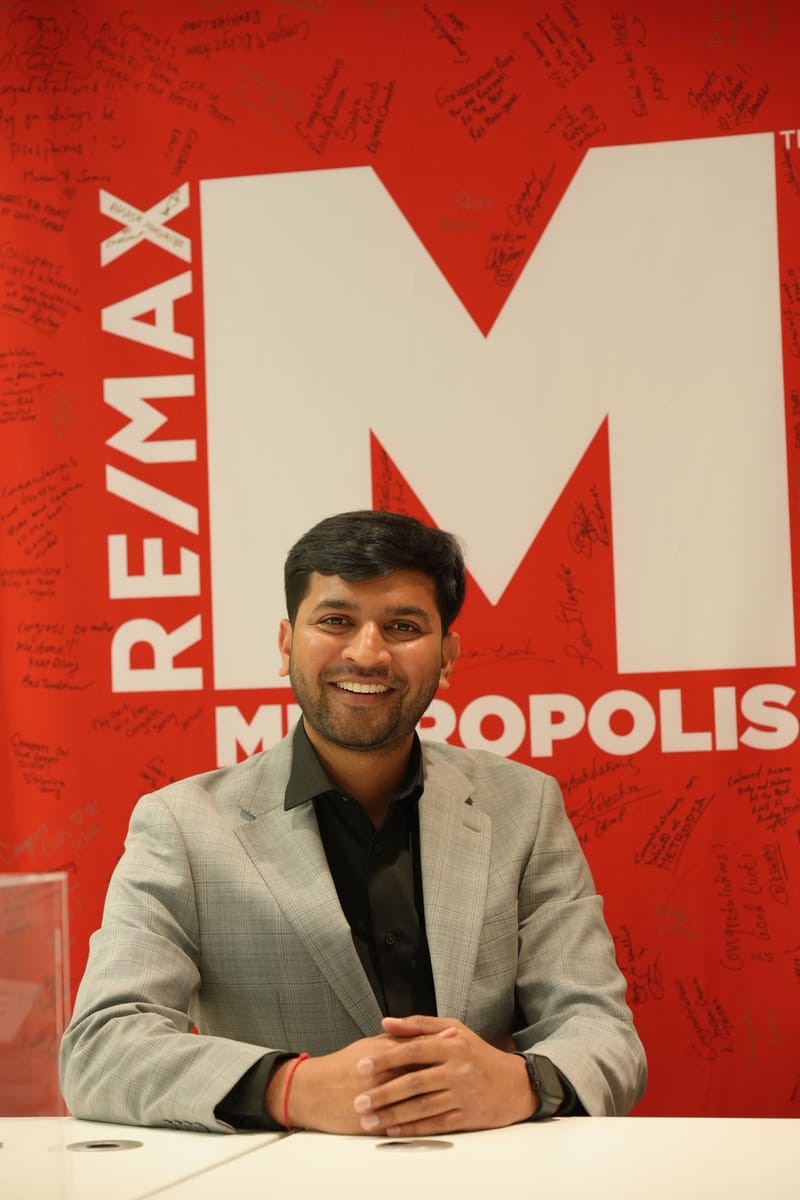 Kaushik Patel smiling at his desk, hands clasped